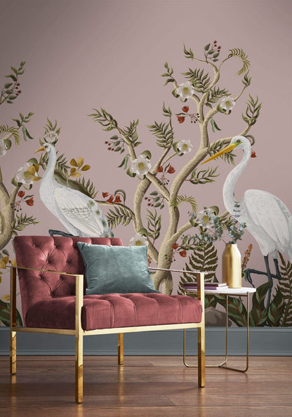 Elegant Heron wallpaper, soft pink and green, with plush pink armchair, gold accents, and wood flooring.