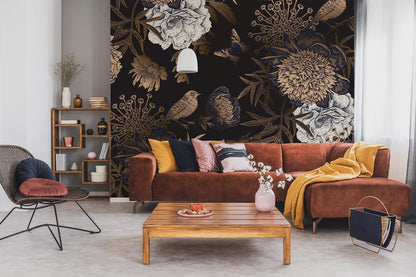 Vintage botanical noir wallpaper with birds, butterflies; brown sofa, wooden coffee table, bookshelf, pendant light.
