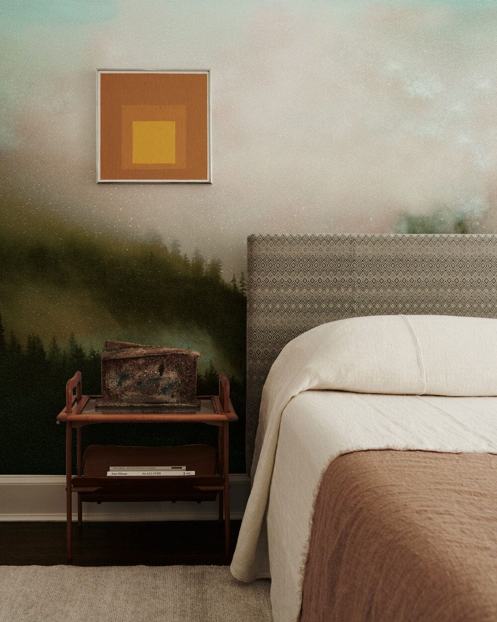Tranquil misty forest mural wallpaper in serene bedroom with upholstered bed, art piece, and soft carpet.