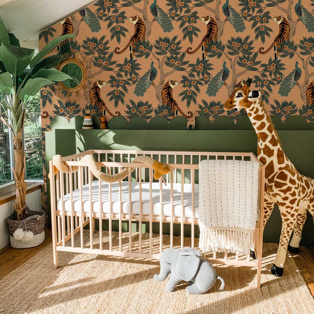 Vintage botanical fauna wallpaper, nursery, natural crib, giraffe toy, earthy tones, green half wall, rug.